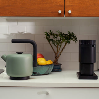 Fellow Clyde Electric Kettle (120V) (1500ml/50oz) in matte green with curved spout on white countertop