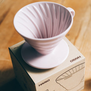 HARIO V60-02 Ceramic Dripper in light pink porcelain with spiral ridges resting on packaging box