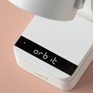 ACAIA Lunar Digital Scale showing "orbit" on sleek black LED display with white textured base surface
