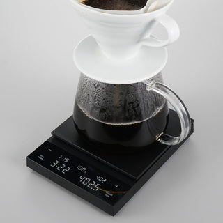 HARIO Polaris Coffee Scale black digital platform showing coffee brewing with glass carafe and white dripper