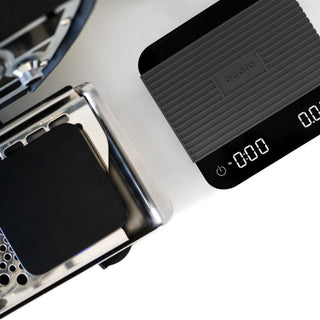 ACAIA Umbra Digital Scale with textured black surface and clear digital display on coffee machine platform