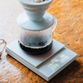 HARIO Polaris Coffee Scale showing precise weight of brewing coffee with glass carafe on wooden surface