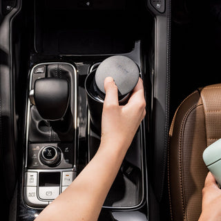 FELLOW Carter Slide Mug 16oz held in car cup holder showing matte black lid and sleek stainless steel body