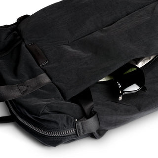 Bellroy Tokyo Totepack Compact in black showing textured recycled fabric and partially open zipper with sunglasses inside