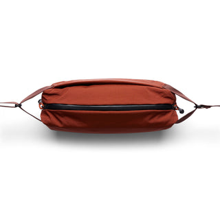 Bellroy Lite Sling in rust color showing front zippered pocket and adjustable straps