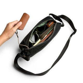 Bellroy Classic Sling 3L in black with organized compartments holding sunglasses and personal items