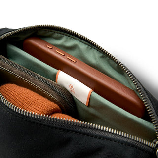 Bellroy Classic Sling 3L showing organized interior with green fabric lining and leather phone case compartment