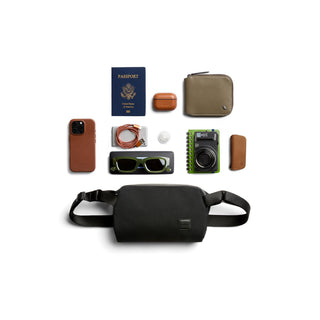 Bellroy Classic Sling 3L black recycled fabric bag with travel essentials laid out above it