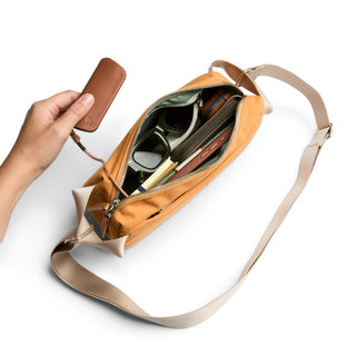 Bellroy Classic Sling 3L in tan with adjustable strap, open to show organized interior compartments
