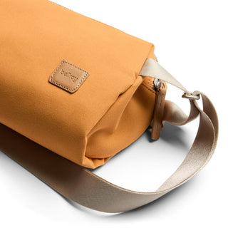 Bellroy Classic Sling 3L in tan recycled fabric with leather logo patch and adjustable strap close-up