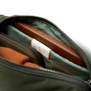 Bellroy Classic Sling 3L in green fabric showing organized interior with smartphone and accessories inside
