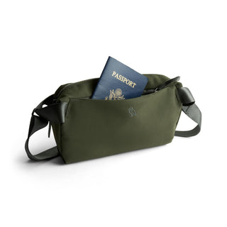 Bellroy Classic Sling 3L in olive green fabric with black strap holding a passport in front pocket