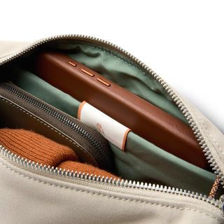 Bellroy Classic Sling 3L in beige with organized green interior holding wallet and phone