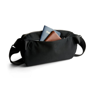 Bellroy Classic Sling 5L in black fabric with leather detail holding passport and wallet
