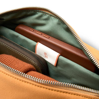Bellroy Classic Sling 5L in tan with green interior showing organized compartments and leather detail