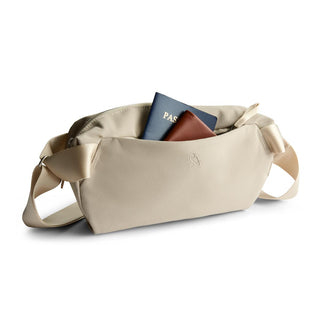Bellroy Classic Sling 5L in beige fabric with front pocket holding passport and wallet