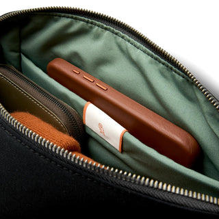 Bellroy Classic Sling 7L showing light green recycled fabric interior with a brown leather accessory inside