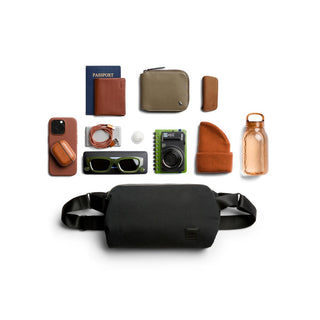 Bellroy Classic Sling 7L black recycled fabric bag with travel essentials neatly arranged nearby