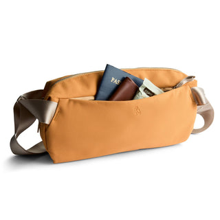 Bellroy Classic Sling 7L in tan with smooth recycled fabric and front zipper pocket holding travel essentials