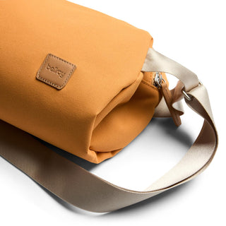 Bellroy Classic Sling 7L in ochre fabric with leather logo patch and adjustable cream strap close-up view