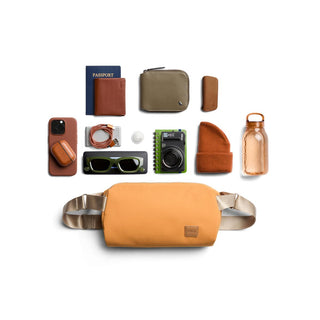 Bellroy Classic Sling 7L in warm tan with smooth fabric and adjustable silver straps shown with daily essentials