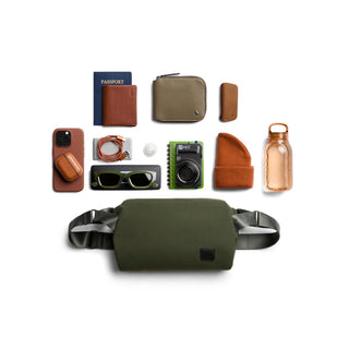 Bellroy Classic Sling 7L in olive green with adjustable straps and compact design shown with travel essentials