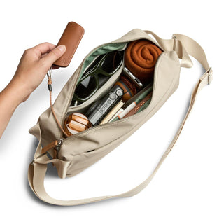 Bellroy Classic Sling 7L in beige showing organized interior with sunglasses and accessories