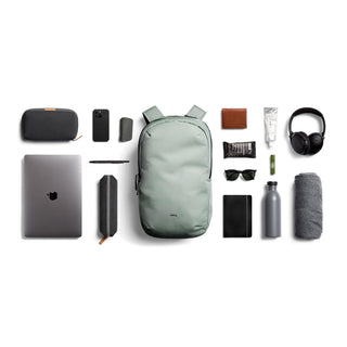 Bellroy Via Backpack in muted green with eco-friendly fabric surrounded by everyday tech and travel essentials