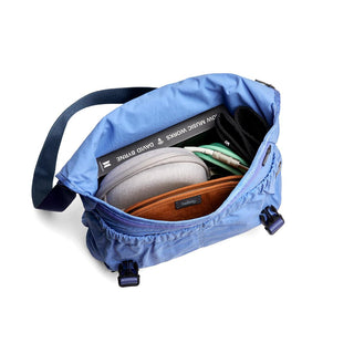 Bellroy Cinch Messenger Bag in blue showing organized interior with tech accessories and book inside