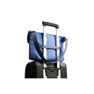 Bellroy Cinch Messenger Bag in blue with adjustable strap secured on suitcase handle