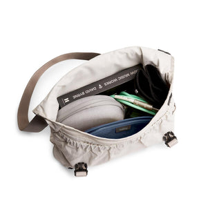 Bellroy Cinch Messenger Bag in light fabric with interior pockets holding accessories and a book