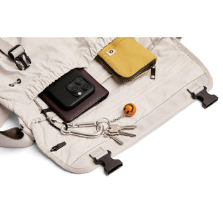 Bellroy Cinch Messenger Bag open showing keys, yellow pouch, and smartphone inside light fabric interior