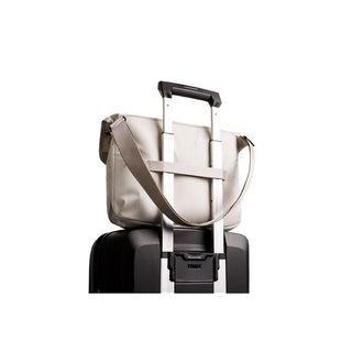 Bellroy Cinch Messenger Bag in light fabric secured on black rolling suitcase handle