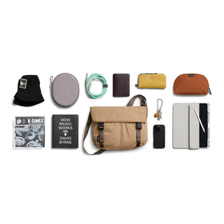 Bellroy Cinch Messenger Bag in tan with essentials neatly arranged on white background