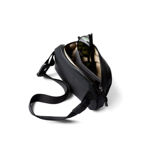 Bellroy Venture Hip Pack 1.5L in black showing open main compartment with sunglasses inside