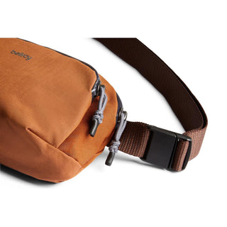 Bellroy Venture Hip Pack 1.5L in rust fabric with adjustable brown strap and dual zipper pull tabs