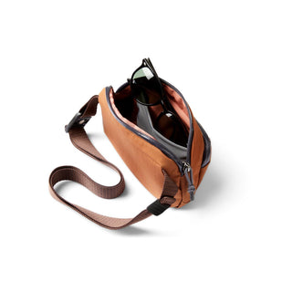 Bellroy Venture Hip Pack 1.5L in brown with adjustable strap and sunglasses inside the main compartment