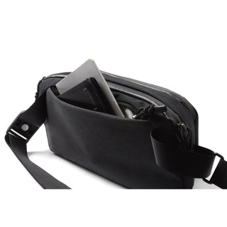 Bellroy Venture Ready Sling 2.5L in black with front pocket holding a tablet and wallet
