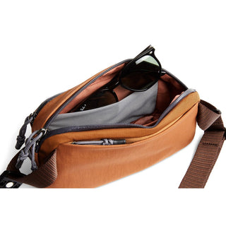 Bellroy Venture Ready Sling 2.5L carrying sunglasses inside open tan recycled fabric pouch