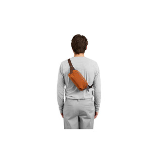 Bellroy Venture Ready Sling 2.5L in rust orange worn across the back with adjustable strap