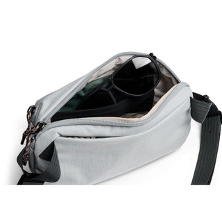 Bellroy Venture Ready Sling 2.5L in light gray showing open main compartment with sunglasses inside