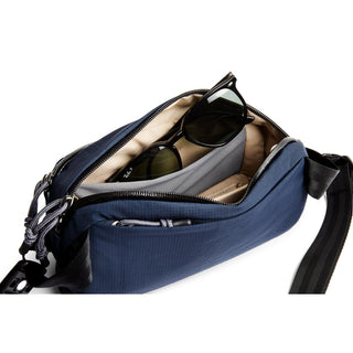 Bellroy Venture Ready Sling 2.5L navy blue bag open showing organized compartments with sunglasses inside