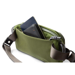 Bellroy Venture Ready Sling 2.5L in olive green with adjustable strap and front pocket holding wallet and notebook