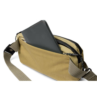 Bellroy Venture Ready Sling 2.5L in tan with adjustable strap and front pocket holding a wallet