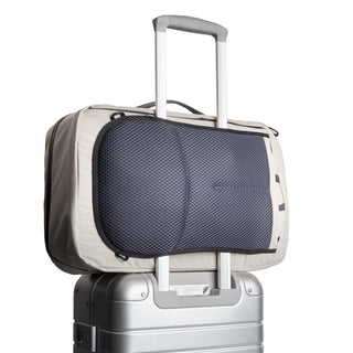 Bellroy Lite Travel Pack 30L beige backpack showing mesh back panel resting on silver suitcase handle