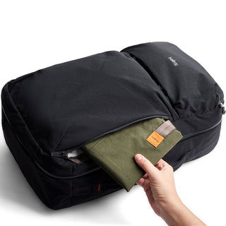 Bellroy Lite Travel Pack 30L in black shows easy access to front compartment with hand holding green pouch
