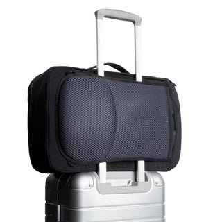 Bellroy Lite Travel Pack 30L in black with mesh back panel attached to silver suitcase handle