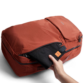 Bellroy Lite Travel Pack 30L in rust with durable recycled fabric and a compact black pouch being removed