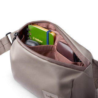 Bellroy Laneway Belt Bag in taupe with organized compartments holding a notebook and wallet inside