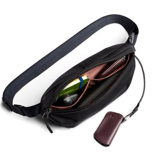 Bellroy Laneway Belt Bag in black showing open compartment with wallet and keys inside